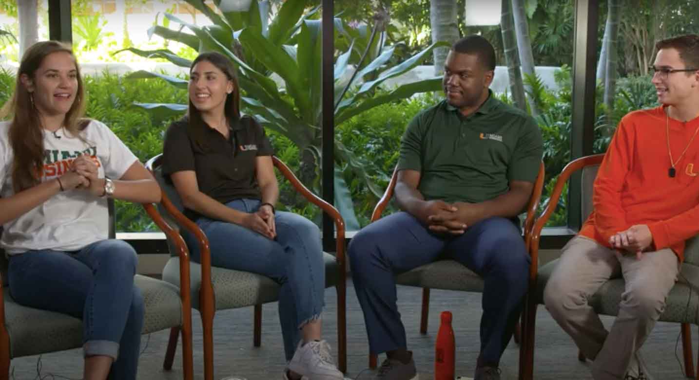 Four students sit in discussion inside a building on campus.
